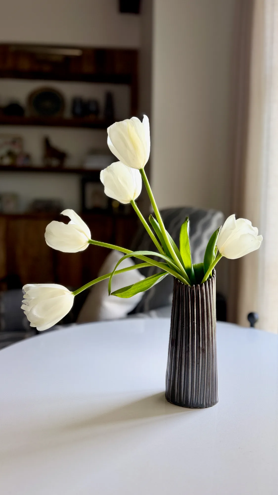 Striated Column No. 1, a slim dark ribbed vessel holding white tulips