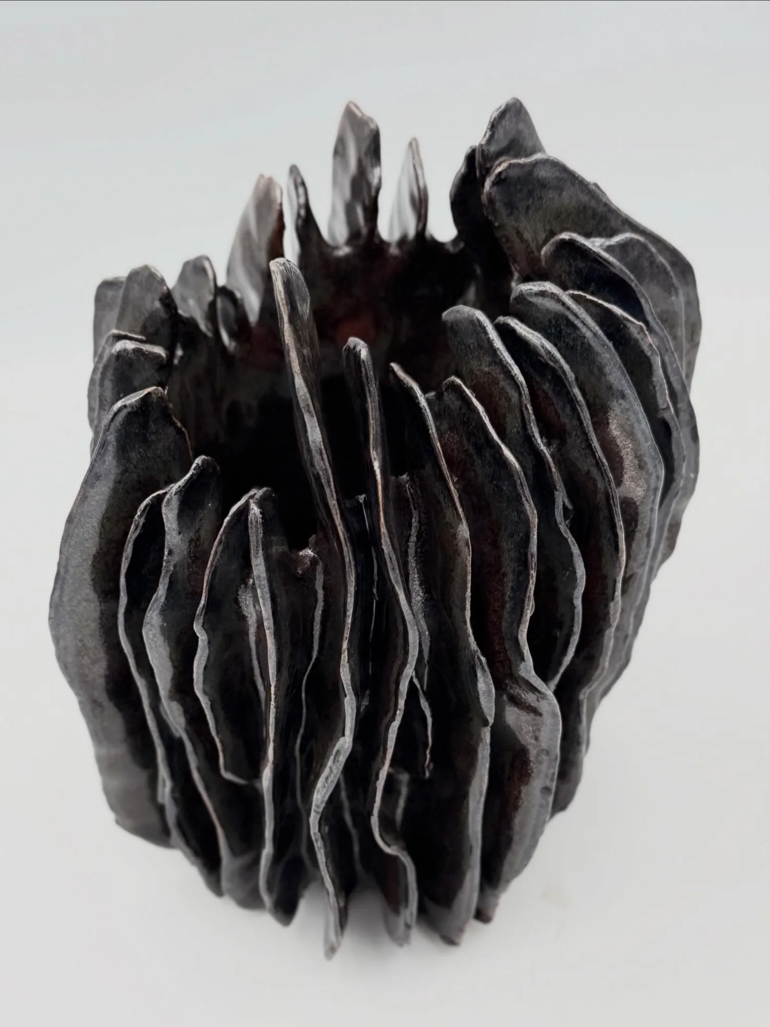 A dark sculpture of tall, tightly packed fluted ribs