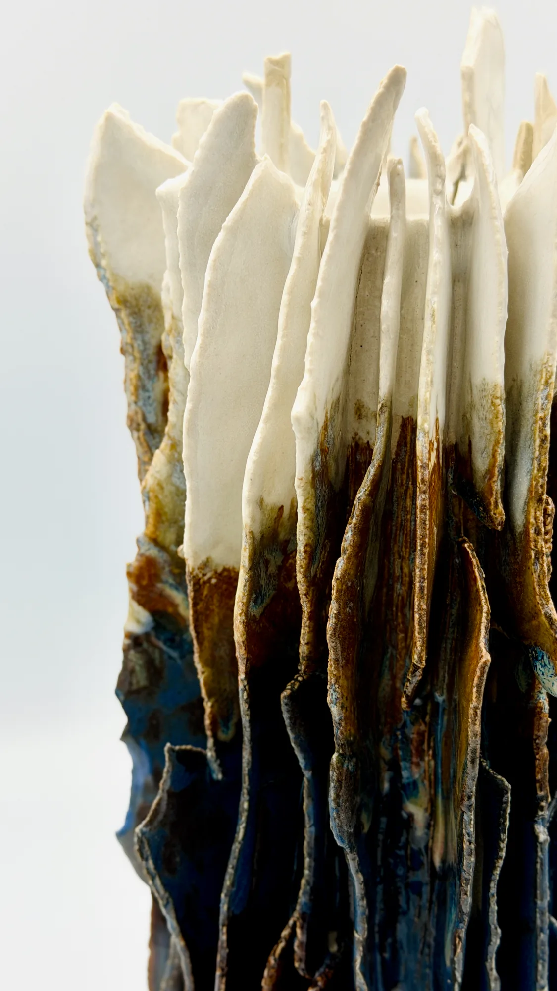 A tall sculpture of white spines rising from layered brown and blue glaze